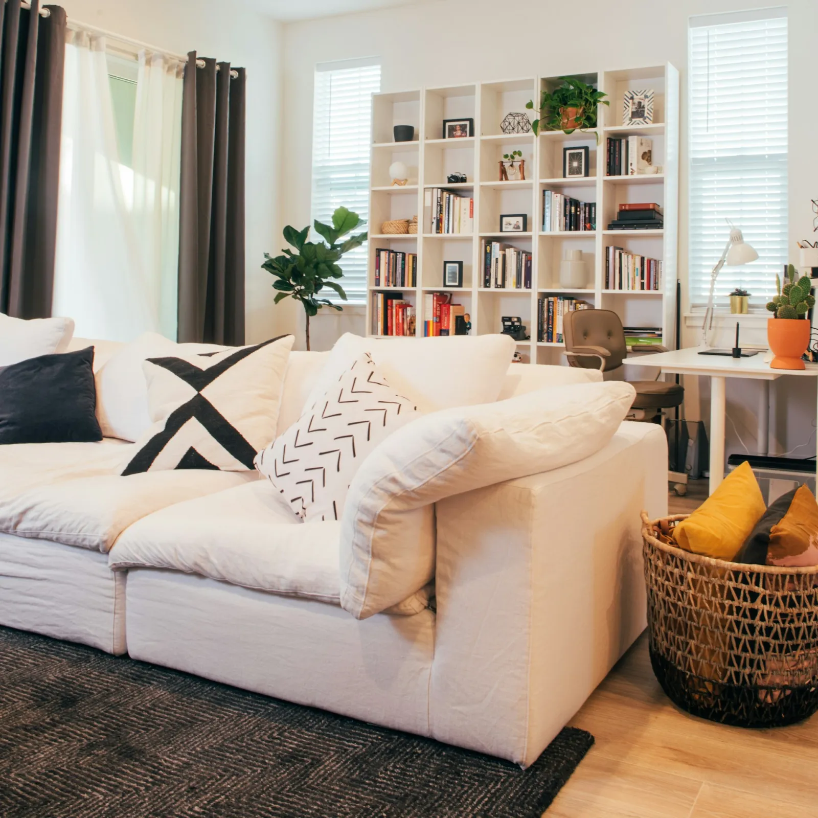 Salon lumineux d’un logement meublé, canapé blanc et bibliothèque